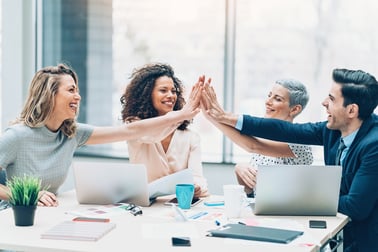 coworkers high-5ing around a table