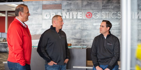 three men talking - the owners of granite logistics in front of a granite logistics sign