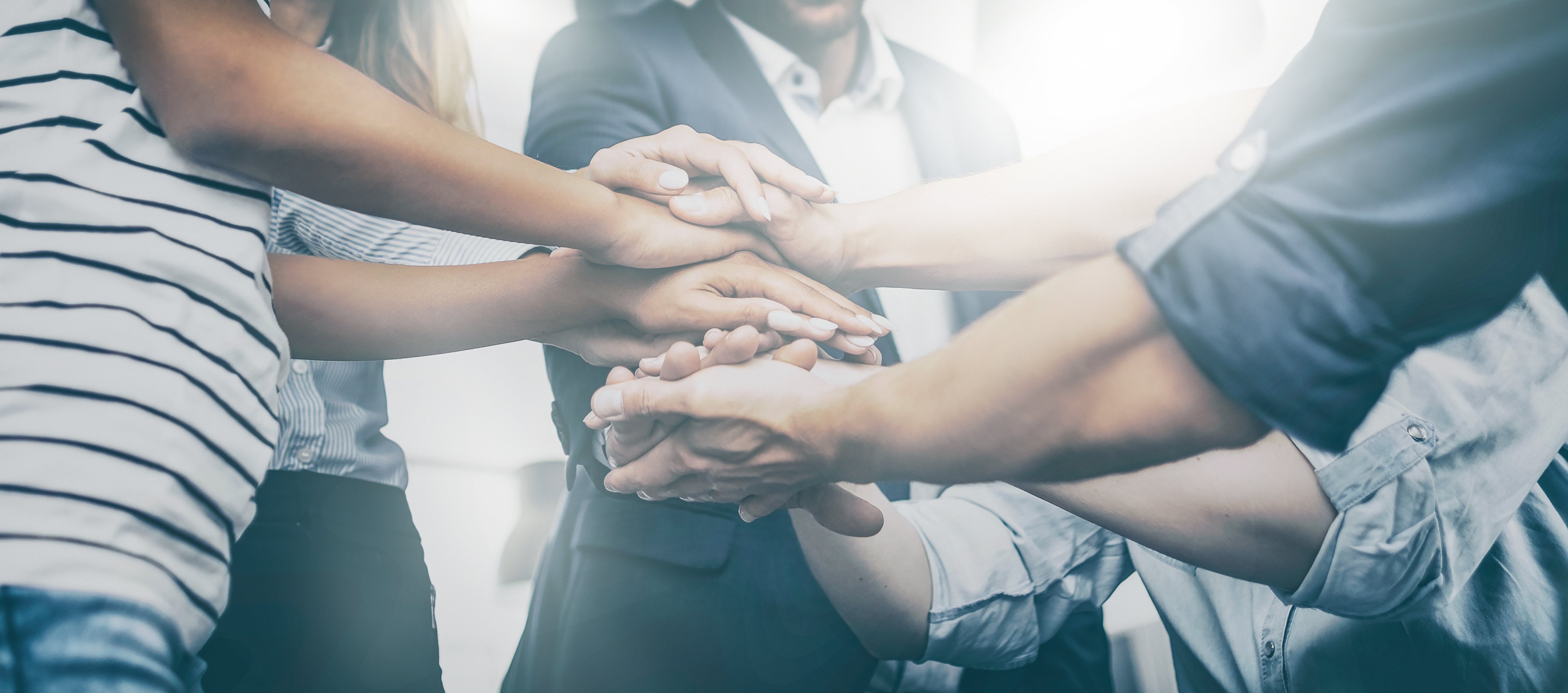 6 people standing in a circle with their hands stacked on top of each other